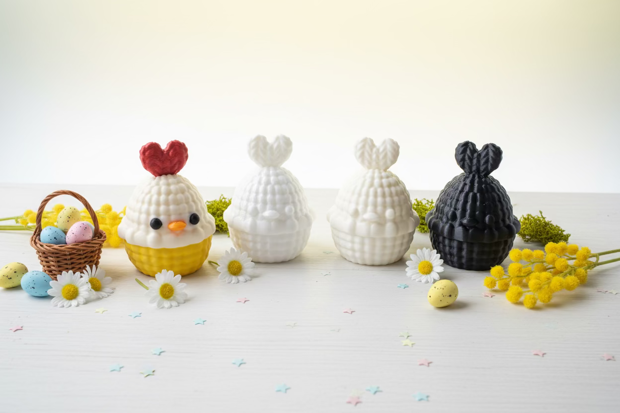 Hähnchen-Ei-Figuren im Stricklook, gelbe, rote, weiße und schwarze Eier auf Tisch