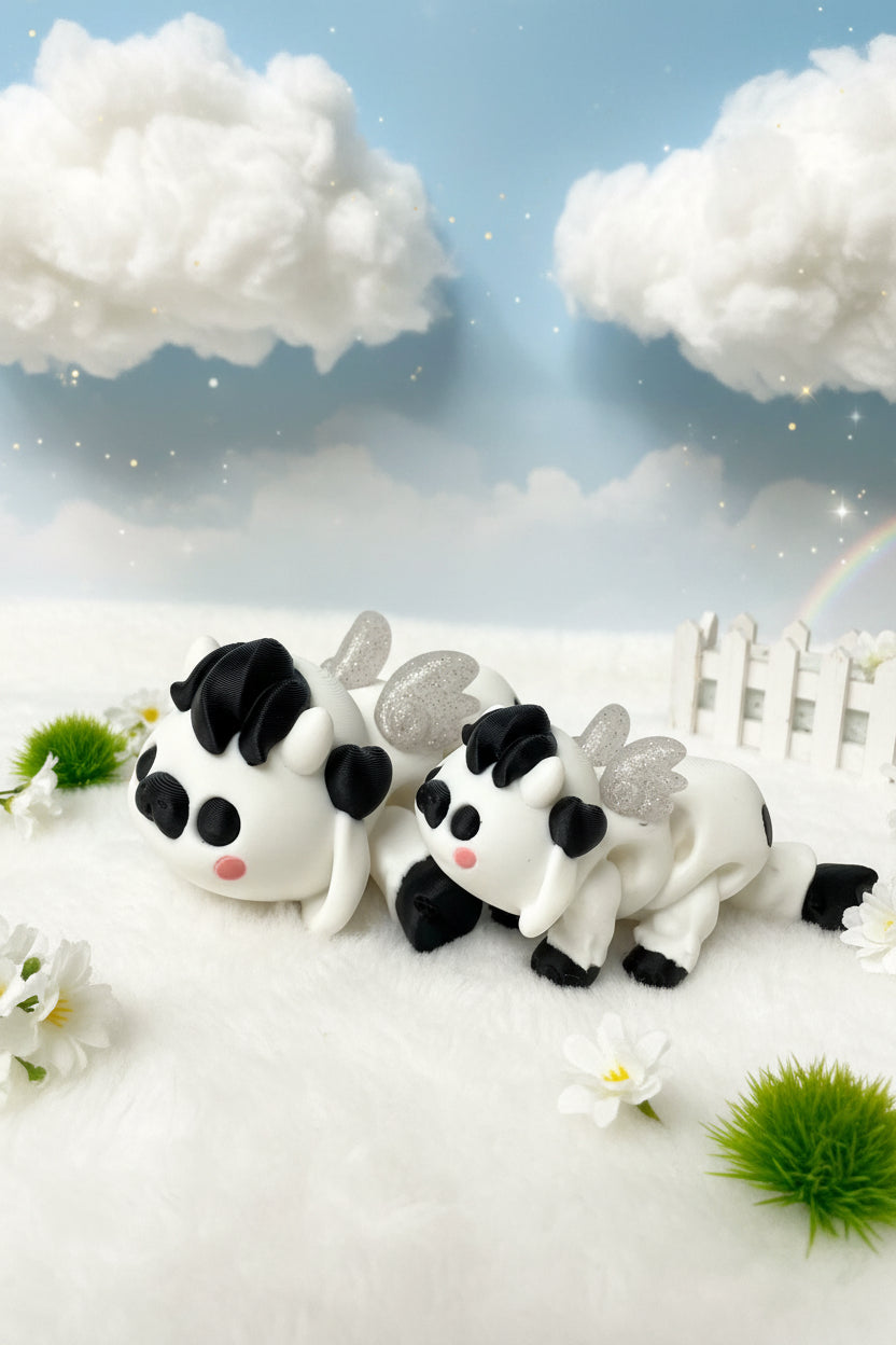 Drei Panda-Dekofiguren mit schwarzen Schleifen und silbernen Flügeln auf Bastelunterlage