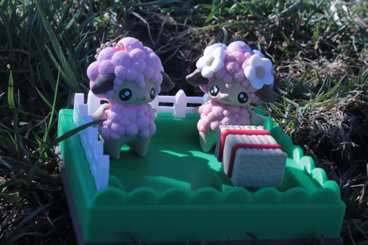 Cute pastel sheep figurines in a green fenced yard with cookies, outdoor setting, kawaii decor