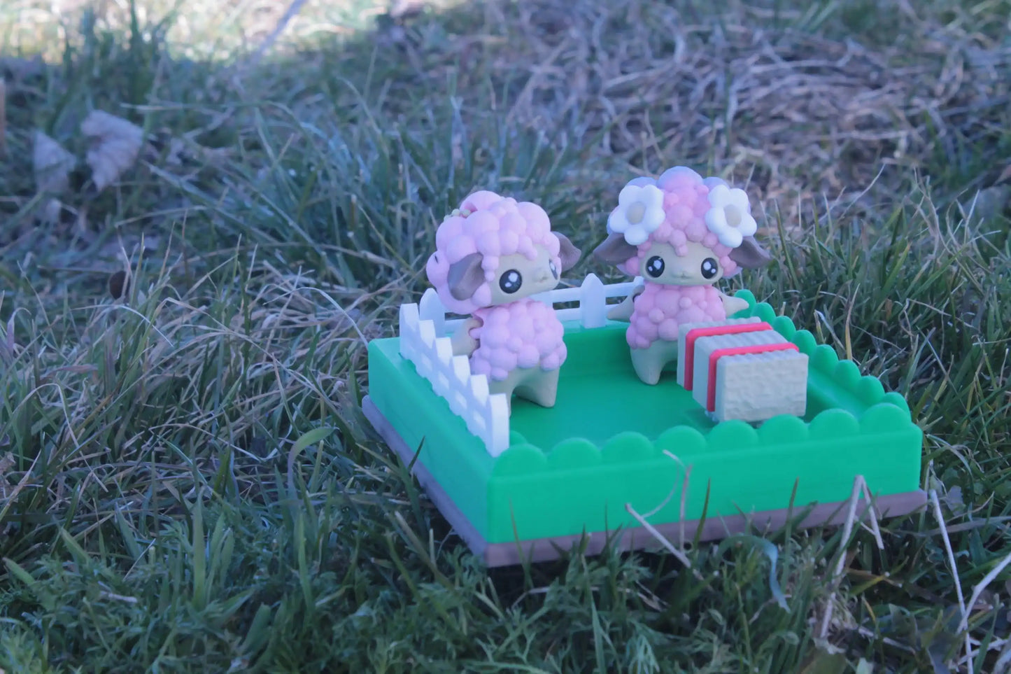 Cute pink sheep figurines in a small green fenced diorama on grass, kawaii décor