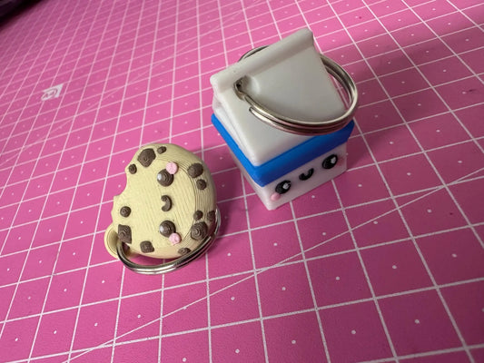 Cute cookie and milk carton keychains with smiling faces on pink grid background