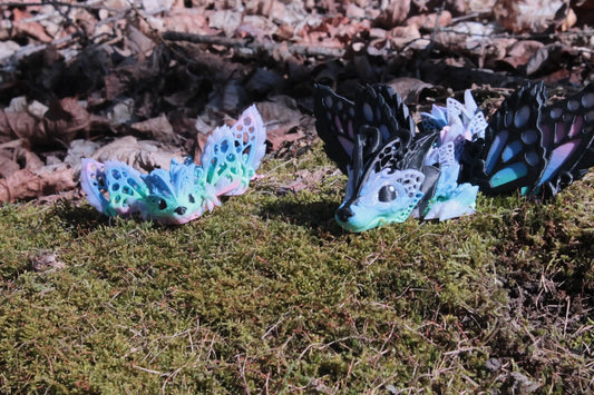 Colorful fantasy dragon figurines with butterfly wings on moss outdoors