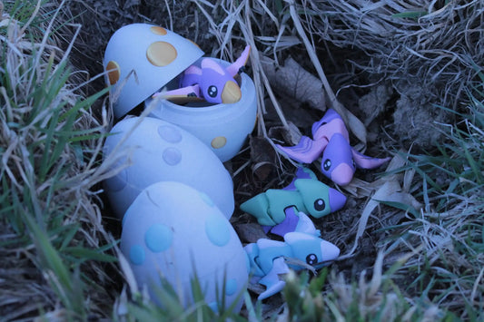 Colorful pastel dragon figurines hatching from speckled eggs in grass and dirt