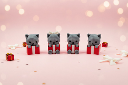 Katzenfigur im 3D-Look, dunkelgrau, mit roter Geschenkbox auf Schneidematte