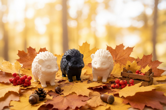 Drei Igel-Ornamente in Weiß, Schwarz und Hellbraun, auf Herbstblättern