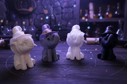 Gestrickte Elefantenfiguren, sitzend: hellgrau, weiß, dunkelgrau und schwarz.