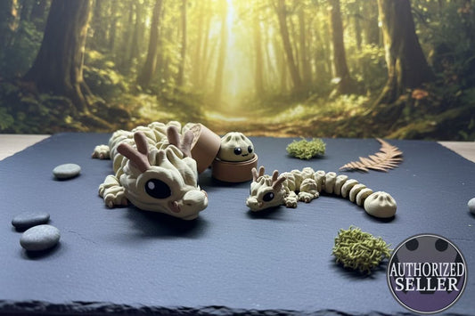 Beiger Dumpling-Babydrache mit schwarzen Augen, auf dunkler Fläche, mehrteilig